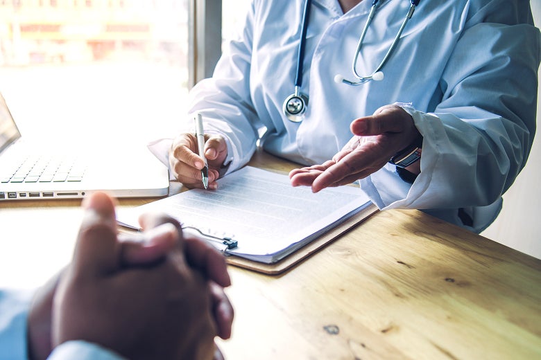 A doctor going over their notes while talking to a patient.
